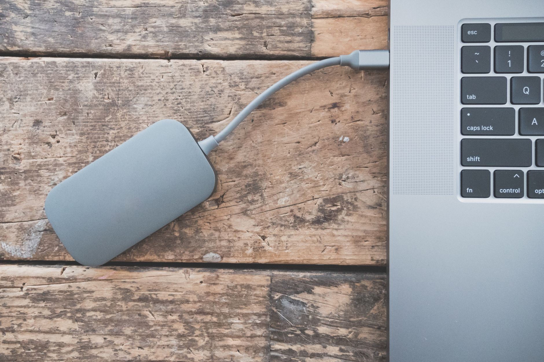Disque dur externe branché à un ordinateur portable via un câble, sur un bureau en bois